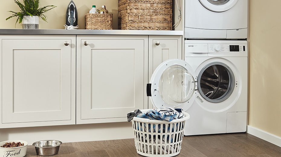 Laundry room with basket of clothes by an open washer