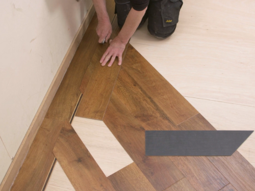 Installer working on fitting a gluedown plank next to a border