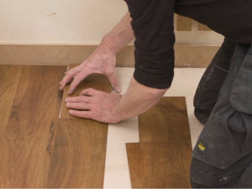 Installer fitting a gluedown plank to the wall