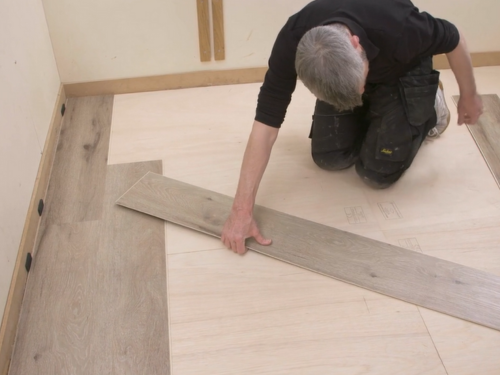 Installer cutting a rigid core plank